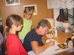 Frau Wenzlaff malt den Außenrand der Schale mit Goldfarbe an.